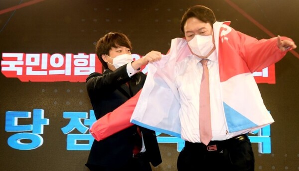 국민의힘 이준석 대표가 5일 서울 용산구 효창동 백범김구기념관에서 열린 제2차 전당대회에서 대선후보로 선출된 윤석열 후보에게 당 점퍼를 입혀주고 있다. / 연합뉴스