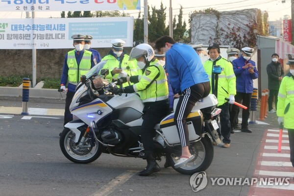 '늦었다' 경찰 오토바이로 수험장 도착한 한 학생이 오토바이에서 내리고 있다.