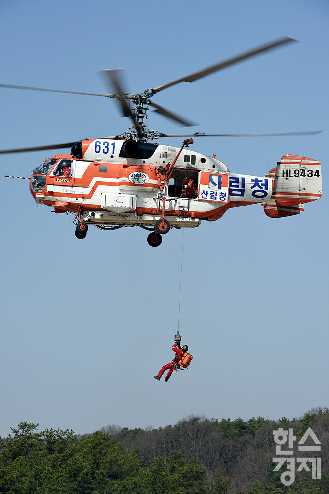 산림청 공중진화대원이 요구조자를 헬기로 이송하기 위해 호이스트를 타고 하강하고 있다. /김근현 기자
