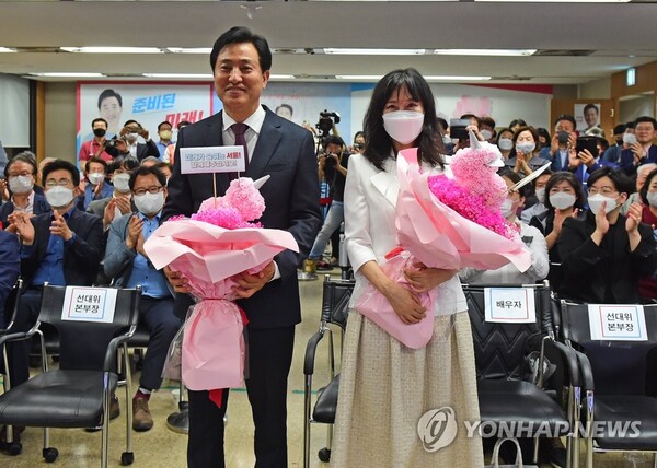 오세훈 국민의힘 서울시장 후보(왼쪽)가 2일 서울 중구 프레스센터에 마련된 캠프 개표상황실에서 당선이 확실시되자 부인 송현옥 씨와 함께 꽃다발을 받고 있다. / 연합뉴스