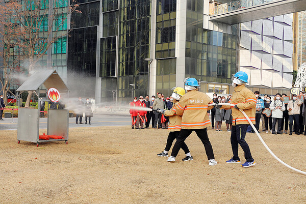 롯데물산이 개최한 소방경진대회 참여자들이 소방호스를 이용해 불을 끄는 연습을 하고 있다. (사진=롯데물산)