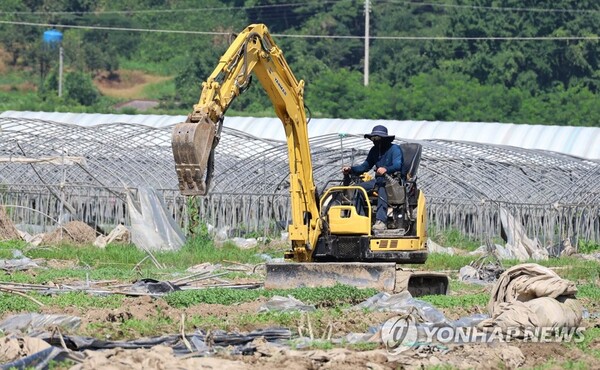 3일 오전 폭염경보가 내려진 충남 청양군 청남면 대흥리 홍수 피해 농가에서 철거 전문 업체가 철거 차량으로 고물을 치우고 있다. 그늘 한 점 없이 내리쬐는 뙤약볕을 막기 위해 근로자는 온몸을 옷으로 휘감았다. /연합뉴스