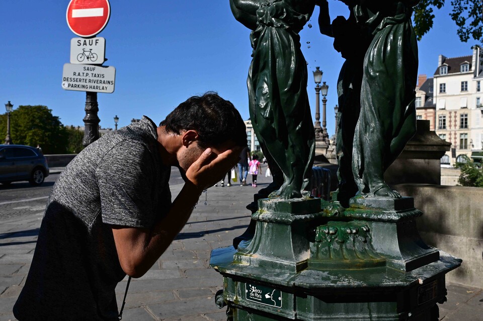 21일(현지시간) 프랑스 파리 적색 폭염 경보가 발령된 가운데, 한 남성이 공공 분수대에서 더위를 식히고 있는 모습. / 연합뉴스