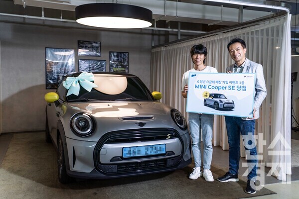 SKT 0 청년요금제 출시 기념 경품 이벤트에서 1등에 당첨돼 BMW 미니 쿠퍼 전기차(Electric SE)를 증정 받은 정태성(왼쪽)씨와 김상범 SKT 유통 담당이 기념촬영을 하고 있다. / SK텔레콤