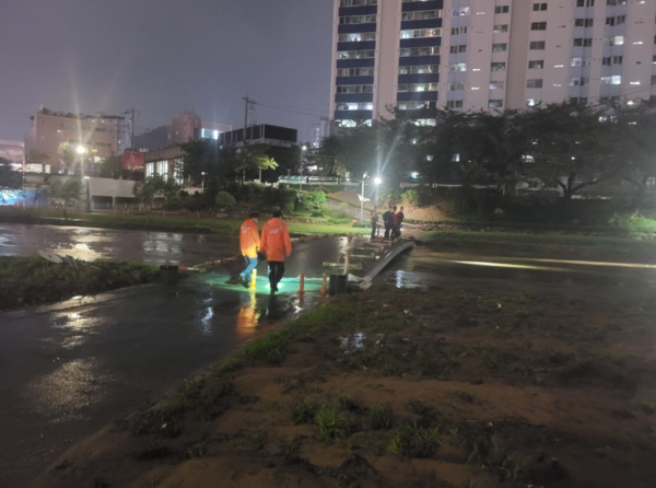 부산 금정구 온천천 산책로에서 한 여성이 폭우로 불어난 물에 휩쓸려 실종된 가운데 소방대원들이 수색작업을 벌이고 있다. / 연합뉴스