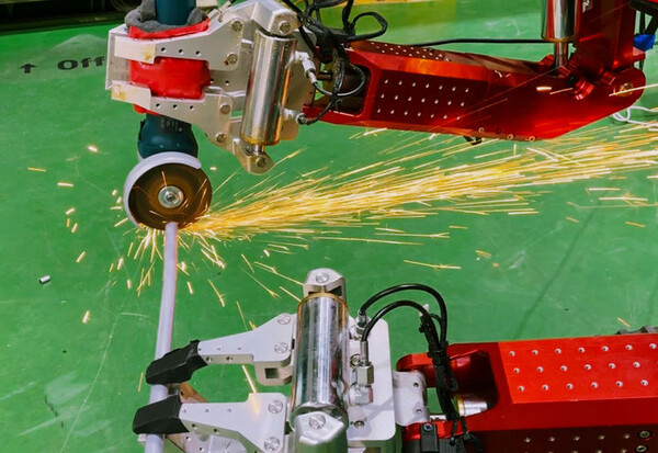 원자력연구원이 자체 개발한 고하중 양팔 로봇 '암스트롱'이 파이프를 절단하고 있는 모습. /원자력연구원