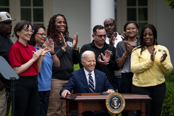 조 바이든 미국 대통령이 14일(현지시간) 백악관 로즈가든에서 철강노조(USW) 등 연관 산업 노조원들이 지켜보는 가운데 중국산 전기차, 배터리, 범용 반도체 등에 대한 관세를 최대 4배 인상하는 내용을 담은 문서에 서명한 뒤 미소를 짓고 있다. / 연합뉴스