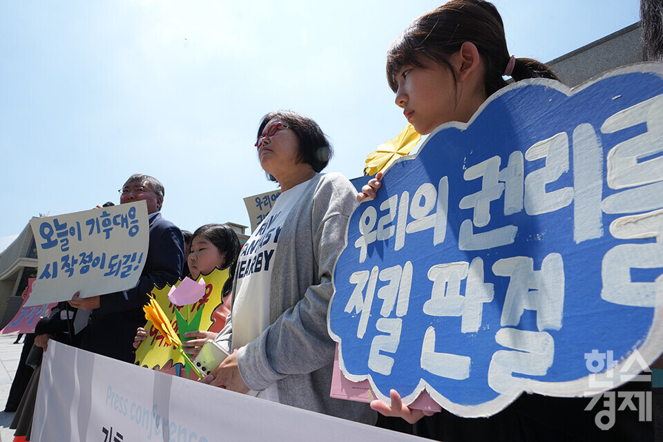 21일 오후 서울 종로구 헌법재판소 정문 앞에서 ‘희망'의 메리골드가 피어난 기후소송 2차 공개변론 기자회견이 열리고 있다. 참석자들이 손 피켓을 들고 있다. /최대성 기자 dpdaesung@sporbiz.co.kr 2024.05.21