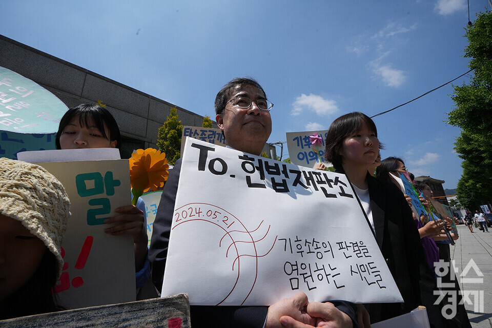 21일 오후 서울 종로구 헌법재판소 정문 앞에서 ‘희망'의 메리골드가 피어난 기후소송 2차 공개변론 기자회견이 열리고 있다. 참석자들이 손 피켓을 들고 있다. /최대성 기자 dpdaesung@sporbiz.co.kr 2024.05.21