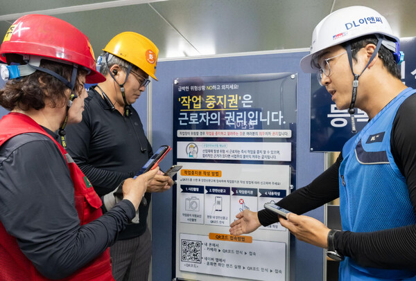 DL이앤씨 현장 안전관리자(오른쪽)가 현장 근로자들에게 안전신문고 접속 및 작업중지권 사용법에 대해 설명하고 있다. /DL이앤씨 제공