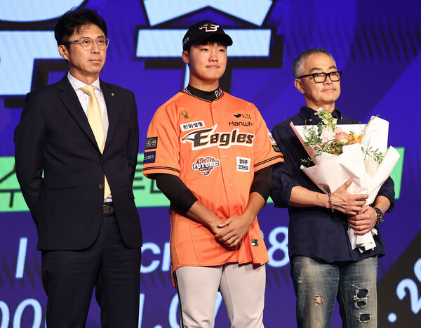 11일 오후 서울 송파구 롯데호텔 월드 크리스탈볼룸에서 열린 2025 KBO 신인 드래프트에서 한화 이글스에 1라운드 2순위 지명을 받은 정우주(전주고)가 손혁 단장으로부터 유니폼을 받고 있다. /연합뉴스