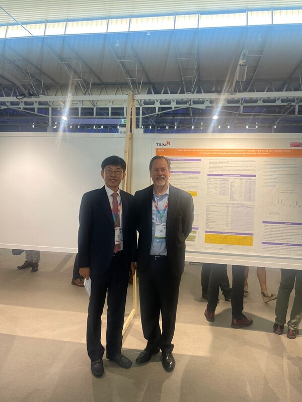 티움바이오 김훈택 대표와 임상 1b상 책임자 Tolcher박사가 포스터 앞에서 포즈를 취하고 있다./티움바이오 제공