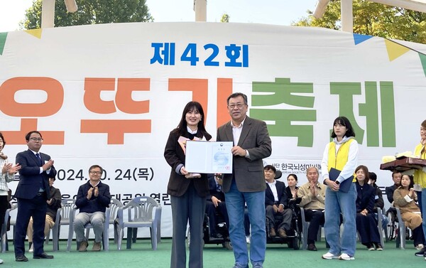 지난 24일 서울어린이대공원에서 개최된 뇌성마비인을 위한 문화예술축제 행사인 '오뚜기 축제'에서 한국뇌성마비복지회 김정우 회장이 유니클로 윤보람 서스테이너빌리티 매니저에게 보건복지부 장관 표창을 수여하고 있다. / 유니클로 제공