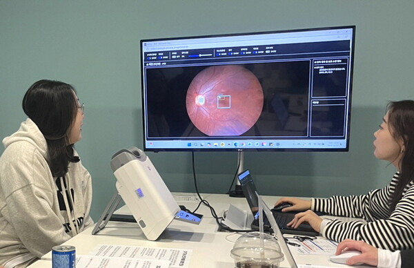 대웅제약 임직원(왼쪽)이 AI 실명질환 진단 보조 솔루션 위스키(WISKY)와 안저카메라 옵티나(OPTiNA Genesis)를 이용해 3대 실명질환 검사를 받은 후, AI 판독 결과를 확인하고 있다./대웅제약 제공