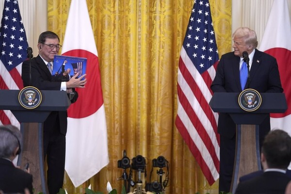 이시바 시게루 일본 총리(왼쪽)가 7일(이하 현지시각) 미국 백악관에서 열린 미일 정상회담에서 도널드 트럼프 미국 대통령에게 그가 지난해 암살 시도를 당했을 때의 사진을 들어 보이고 있다. /연합뉴스