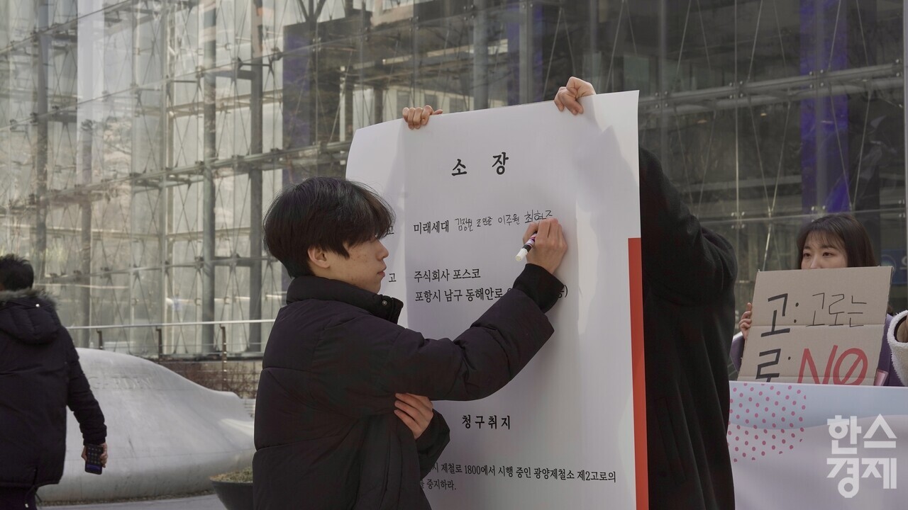 ▲청소년들이 '광양제철소 2고로 개수 공사 중지 청구 소송' 소장에 서명하는 퍼포먼스를 하고 있다. (사진=광양환경운동연합)