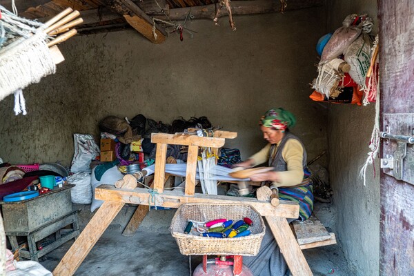 집이 몇 채 없는 외딴 마을인 디가온의 1층 헛간 같은 공간에서 젊은 아낙네가 베틀에 앉아 수작업으로 천연색의 직물을 짜고 있다.
