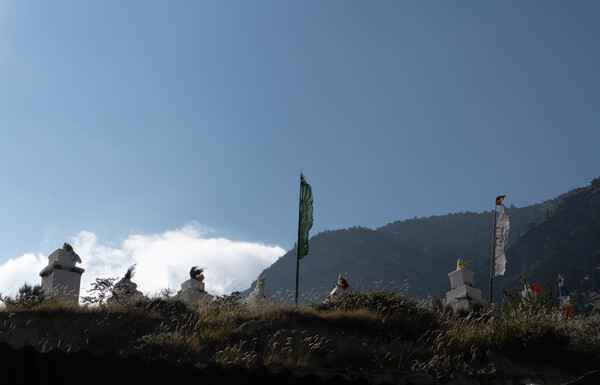 석양빛을 받으며 언덕 위에 서있는 불탑과 룽다.