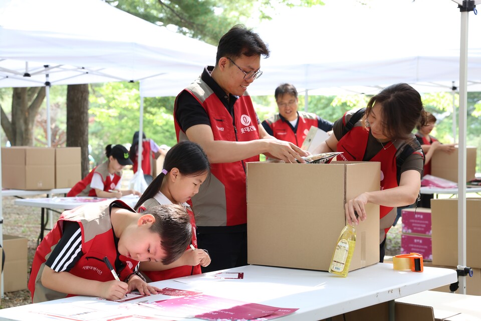 롯데건설 ‘샤롯데 봉사단’이 국가유공자 보훈가정을 위한 응원카드를 작성하고 기부물품을 포장하고 있다./롯데건설