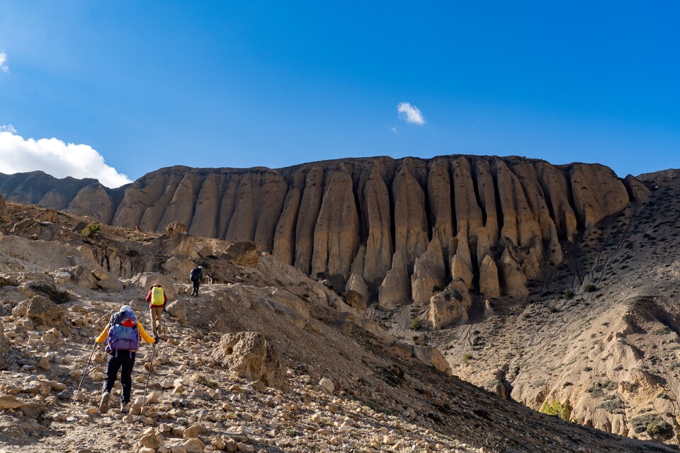 파이프 오르간 형태의 거대한 석주형 절벽을 향해 오르막 너덜 길을 오르는 트레커.