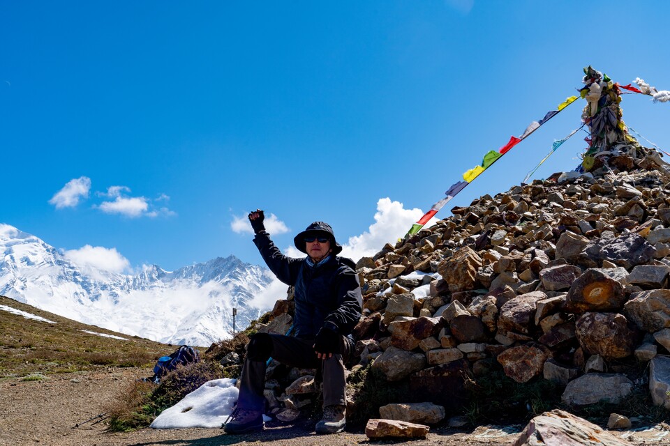 트레커가 정상 마니퇴 돌에 앉아 파이팅을 외치고 있다.