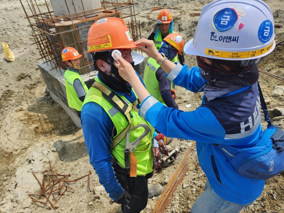 DL이앤씨 현장 안전보건관리자가 근로자의 체온을 측정하고 건강상태를 확인하고 있다./DL이앤씨