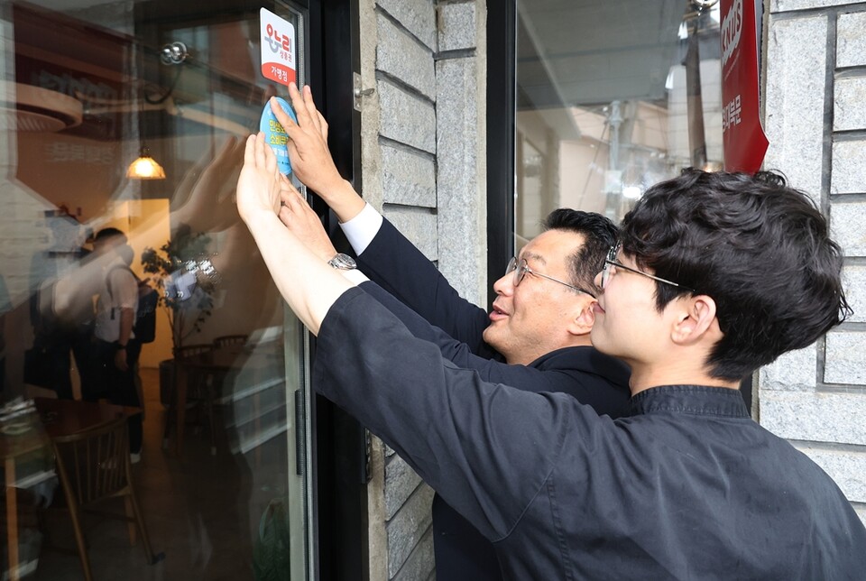 한순기 행정안전부 지방재정경제실장이 지난달 16일 오전 민생회복 소비쿠폰 1차 지급을 앞두고 민생회복 소비쿠폰 가맹점 스티커 부착 및 홍보물 배부를 하고 있다./행정안전부