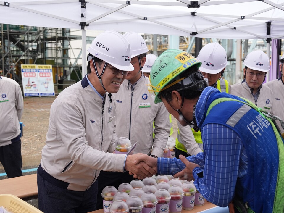 이용배 현대로템 대표(왼쪽)가 14일 당진제철소 내에 위치한 3코크스 건식소화설비(CDQ) 건설 현장에 마련된 빙수차 앞에서 근로자들에게 컵빙수를 전달하고 있다./현대로템