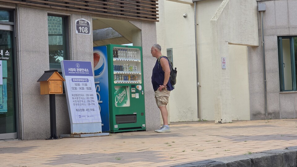 작동하지 않는 자동판매기 앞 무더위 속 타는 갈증해소를 위해 다가선 외국인 관광객이 망연자실한 표정으로 바라보고 있다./ 김두일 기자
