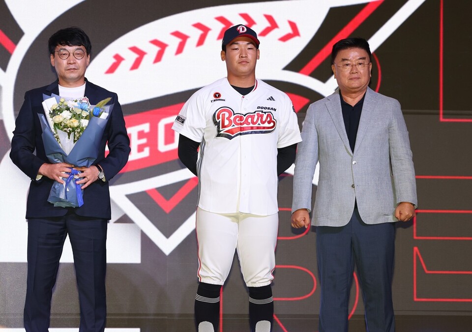 김주오(가운데)가 전체 7순위로 호명된 뒤 두산 유니폼을 입고 단상에서 포즈를 취하고 있다. /두산 베어스 제공