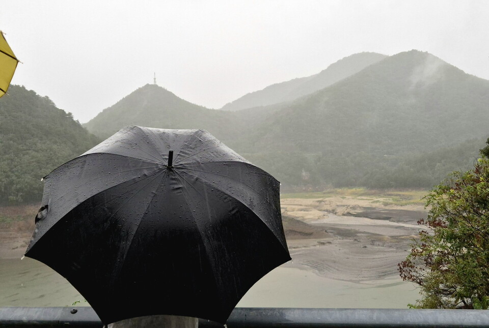 13일 가뭄으로 메마른 강원 강릉시 오봉저수지 일원에 비가 내리자 시민들이 우산을 쓰고 바라보고 있다./연합뉴스.