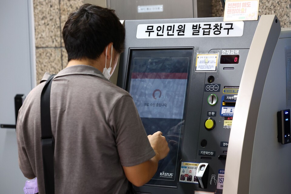 26일 국가정보자원관리원 대전 본원에 있는 전산실에서 발생한 화재로 정부 업무시스템 647개가 가동이 중단된 것으로 파악됐다. 27일 서울 시내 한 지하철역에 설치된 무인민원발급기에서 한 시민이 서류가 발급되지 않아 '자료 수신 중입니다'라는 문구가 나오는 화면을 바라보고 있다./연합뉴스