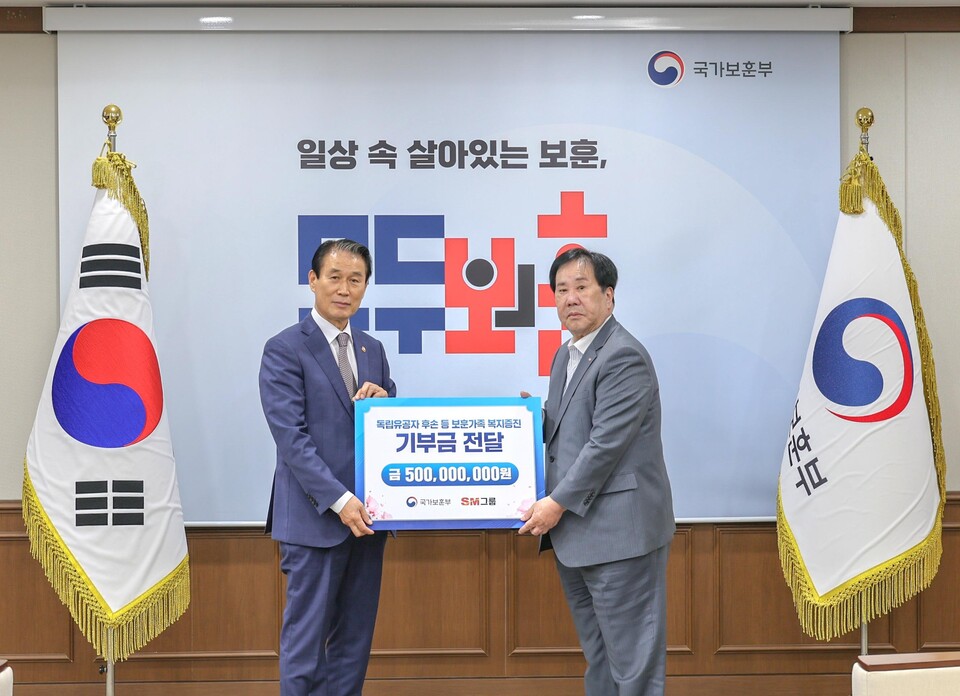 SM그룹 우오현 회장(오른쪽)이 13일 오전 정부세종청사에서 열린 국가보훈부의 전 국민 보훈 기부 프로젝트 ‘모두의 보훈 드림’ 후원금 전달식에서 권오을 장관과 기념촬영을 하고 있다./SM그룹