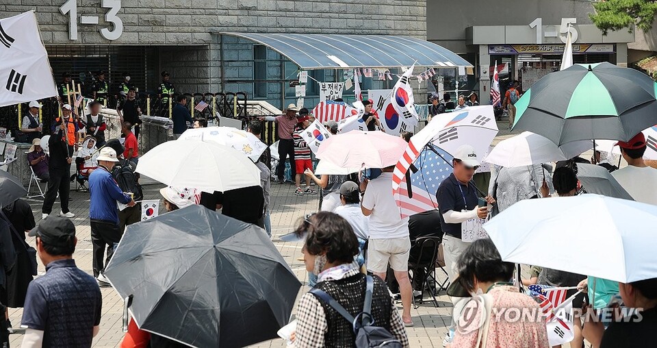 6·3 지방선거 당시 잠실 개표소로 사용된 서울 송파구 올림픽공원 핸드볼경기장 앞에서 28일 투표용지 부족 사태 규탄 봉쇄 시위 참가자들이 우산을 쓰고 구호를 외치고 있다. /연합뉴스